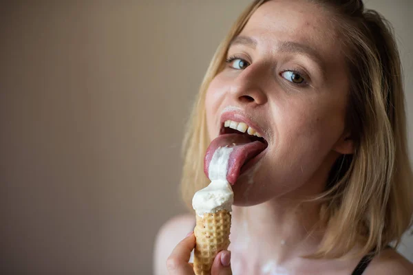 Sexy bionda lecca un cono cialda. Il gelato si sta sciogliendo, drenando eroticamente attraverso il corpo di una donna attraente. Bella ragazza in biancheria intima nera spalmata di gelato. Primo piano — Foto Stock