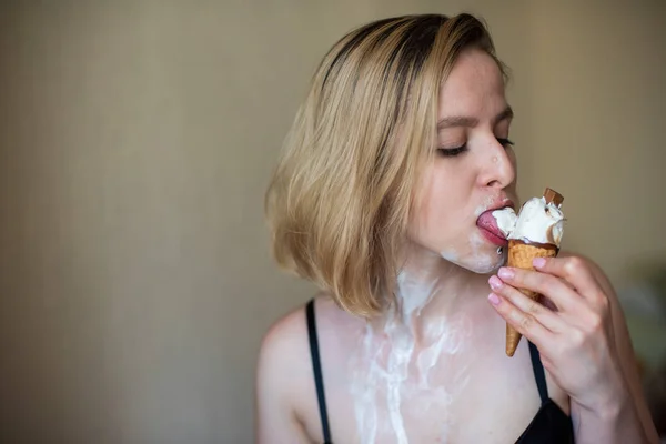 Sexy bionda lecca un cono cialda. Il gelato si sta sciogliendo, drenando eroticamente attraverso il corpo di una donna attraente. Bella ragazza spalmata di gelato. — Foto Stock