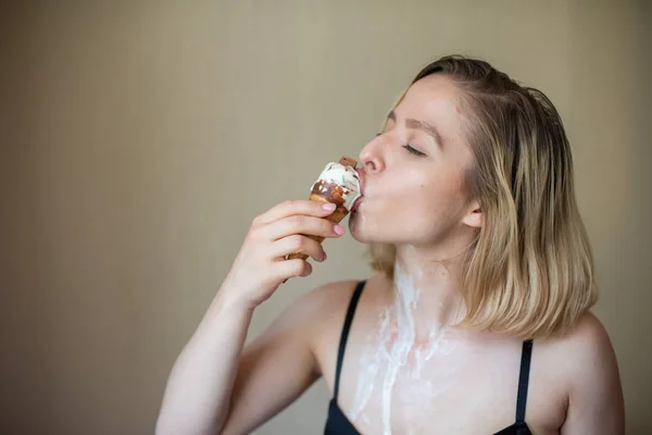 Sexy rubia lame un cono de gofre. El helado se está derritiendo, drenando eróticamente el cuerpo de una mujer atractiva. Hermosa chica untada con helado. — Foto de Stock