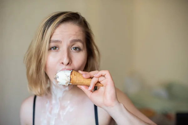 Sexy bionda lecca un cono cialda. Il gelato si sta sciogliendo, drenando eroticamente attraverso il corpo di una donna attraente. Bella ragazza spalmata di gelato. — Foto Stock