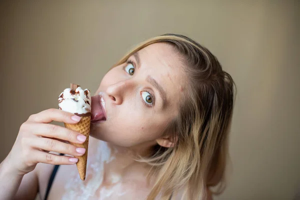 Sexy bionda lecca un cono cialda. Il gelato si sta sciogliendo, drenando eroticamente attraverso il corpo di una donna attraente. Bella ragazza spalmata di gelato. — Foto Stock