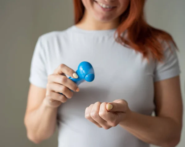 La ragazza dai capelli rossi asciuga lo smalto con un ventilatore da tasca. Una donna inventiva si fa una manicure a casa sua. Un piccolo fan. Donna felice che soffia su una manicure luminosa dal flusso d'aria . — Foto Stock