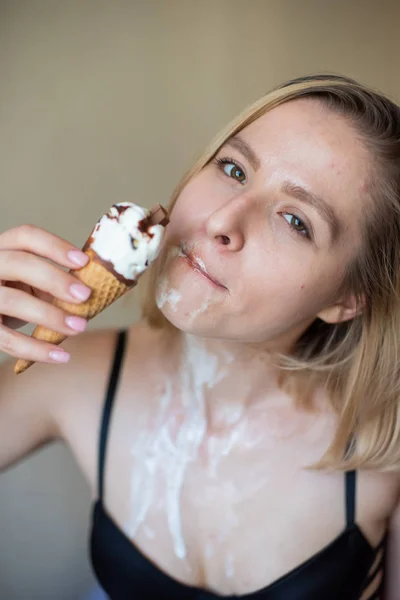 Sexy bionda lecca un cono cialda. Il gelato si sta sciogliendo, drenando eroticamente attraverso il corpo di una donna attraente. Bella ragazza spalmata di gelato. — Foto Stock