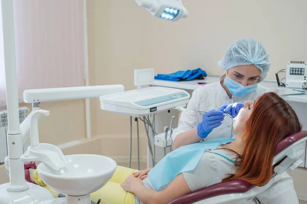 Una dentista che controlla la carie della paziente. Donna dai capelli rossi visitata da un medico. La ragazza farà la salute dei denti . — Foto Stock