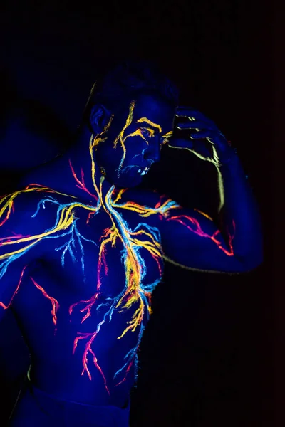 Modelli UV body art del sistema circolatorio su un corpo umano. Sul petto di un atleta muscolare, vene e arterie sono disegnate con coloranti fluorescenti. Il bodybuilder raddrizzato i bicipiti — Foto Stock