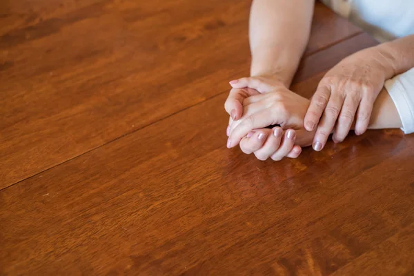 Elderly mother and her daughter holding hands while sitting at the table.Close up on women of different generations holding hands. Close Up Shot Of Mother And Daughter's Hands Holding — Stock Photo, Image