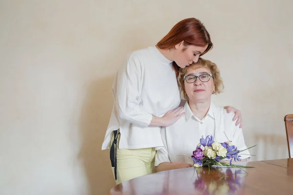 Dcera dává květiny dospělé matce. Dcera dává květiny matce a ubývá jí. Trávit čas spolu, oslavovat doma o víkendech. Den matek — Stock fotografie