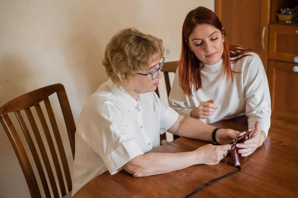 Mutter und Tochter trugen helle Kleidung und beherrschten das Smartphone. Eine Frau zeigt, wie man ein Smartphone für seine betagte Mutter benutzt — Stockfoto