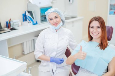 Dental tedavi sonrası bir ofiste kadın dişçi ve Kızıl saçlı bir hasta, mutlu yüzler ile kameraya bakıyor. Onu doktoru ile mutlu kadın barınak için işaret gösterir aldıktan sonra.