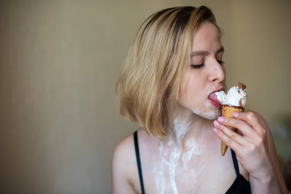 Loira sexy lambe um cone de waffle. Sorvete está derretendo, eroticamente drenando através do corpo de uma mulher atraente. Menina bonita manchada com sorvete. — Fotografia de Stock