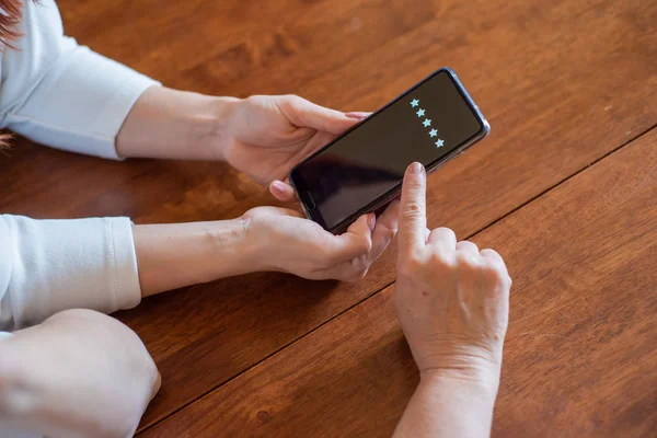 Two women vote in a smartphone while sitting at the table. The hands of mother and daughter, holding the phone and arrange the rating, Zero stars. Experience . Close-up phone