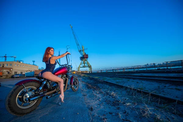 Mujer pelirroja en lencería sexy en tacones altos se sienta en una motocicleta. Atractiva chica pelirroja se sienta en una motocicleta al atardecer — Foto de Stock