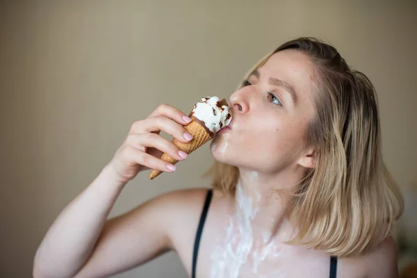 Сексуальная блондинка лижет вафельный рожок. Мороженое тает, эротически просачиваясь через тело привлекательной женщины. Красивая девушка, размазанная мороженым. — стоковое фото