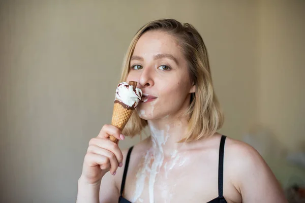 Loira sexy lambe um cone de waffle. Sorvete está derretendo, eroticamente drenando através do corpo de uma mulher atraente. Menina bonita manchada com sorvete. — Fotografia de Stock