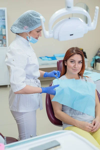 Giovane bella dentista femminile sta parlando con la sua paziente. Donna dai capelli rossi che sorride al ricevimento dal dottore. Servizi dentistici . — Foto Stock