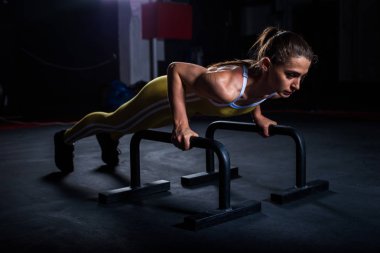 Spor salonunda barlar ile yatay şınav yapıyor sarı sıkı spor üniformagenç atletik kız
