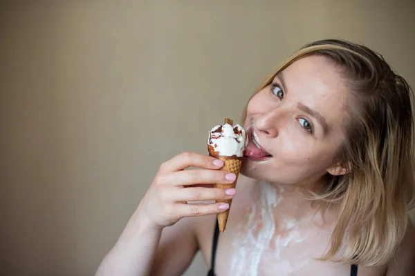 Sexy bionda lecca un cono cialda. Il gelato si sta sciogliendo, drenando eroticamente attraverso il corpo di una donna attraente. Bella ragazza spalmata di gelato. — Foto Stock