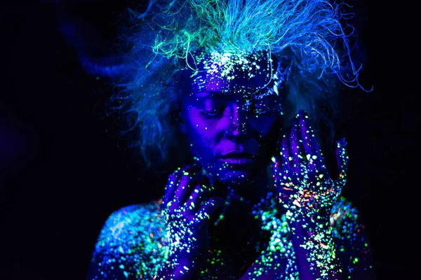 Koyu arkaplanda gür saç stili olan çok güzel bir kızın yüzünde UV vücut sanatı. Boşluk şekli.