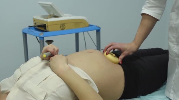 Bir jinekolog hamile bir kadını muayene ediyor. Fetal doppler kalp bakımı. Doktor muayenehanesindeki hasta. Kalp atışlarının değerlendirilmesi ve fetal kardiyak aktivitelerin kontrolü. Sağlıkla ilgili endişeler. — Stok video