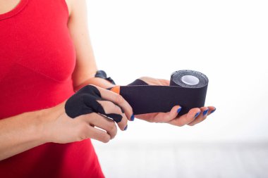 Hastalıklı bir bilek için fizyoterapi. Alternatif tıp. Yaralanmaları olan sporcular için yapışkan bant. Yaralı bir parmak için destek. Beyaz bir arka plan üzerinde Kadın eller kinesiotape bir rulo tutun.