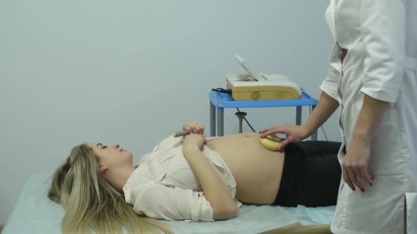 A gynecologist examines a pregnant woman. Fetal doppler heart auscultation. Patient at doctor office. Assessment of heartbeat and control of all fetal cardiac activity. Concern about the health. — Stock Footage Gynecologist Examines Pregnant Woman Fetal Doppler Heart Auscultation Patient Doctor Stock Footage