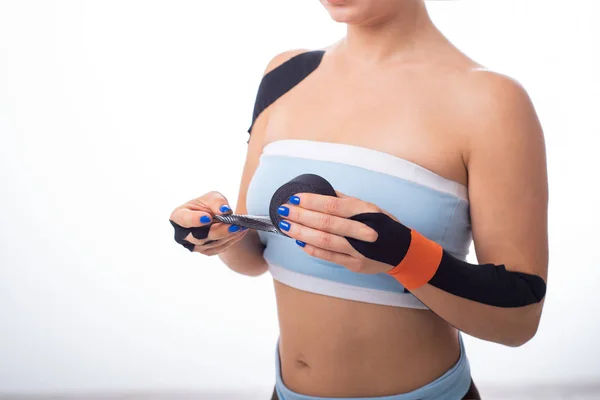 Kadın atlet bileğine teip koyar. Kineziology, eklem ve tendon yaralanmaları için alternatif tedavi. Bir kadın elinde bir rulo kineziotape tutuyor. Lenfdrenajı. Yakın çekim. — Stok fotoğraf