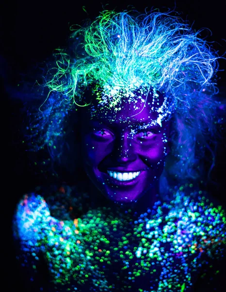 Body art e lenti a contatto che brillano nella luce ultravioletta. Donna sorridente, dipinta in polvere fluorescente. Stelle negli occhi — Foto Stock