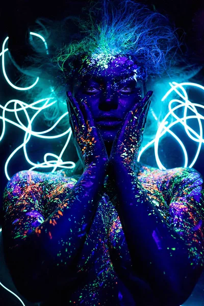 La ragazza è l'immagine del diavolo, lenti a contatto e con le corna. Donna in vernice UV. Polvere fluorescente. Body art incandescente nella luce ultravioletta. Stelle negli occhi . — Foto Stock