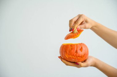 Cadılar Bayramı'nda balkabağı tutan kadın elleri. Bir kadının yakın çekim jack-o'-fener kapağı tüm azizarifesinde beyaz bir arka plan üzerinde açar. ön görünüm.