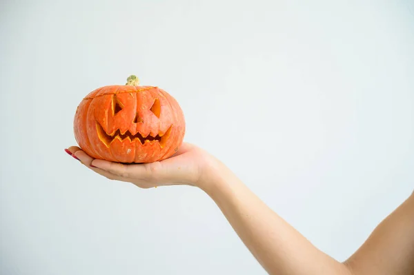 Weibliche Hand, die einen Kürbis zu Halloween hält. Nahaufnahme Jack-o-Laterne Cover auf weißem Hintergrund am Vorabend aller Heiligen. Frontansicht. Hand für den Urlaub gemacht. Trick oder Treatment. — Stockfoto