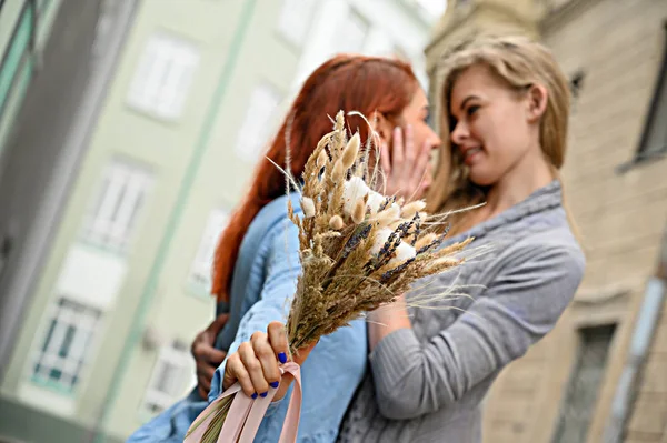 Gleichgeschlechtliche Beziehungen. glückliches lesbisches Paar mit getrockneten Blumen. Zwei schöne Frauen umarmen sich bei einem Date zärtlich. Strauß im Vordergrund. aus nächster Nähe zu ein paar Hands.lgbt. — Stockfoto