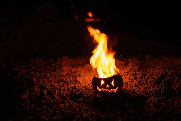 Tungor av flamma i en pumpa. Jack-o-Lantern i brand på en svart bakgrund. Halloween symbol på marken. Bus eller godis. Närbild. — Stockfoto