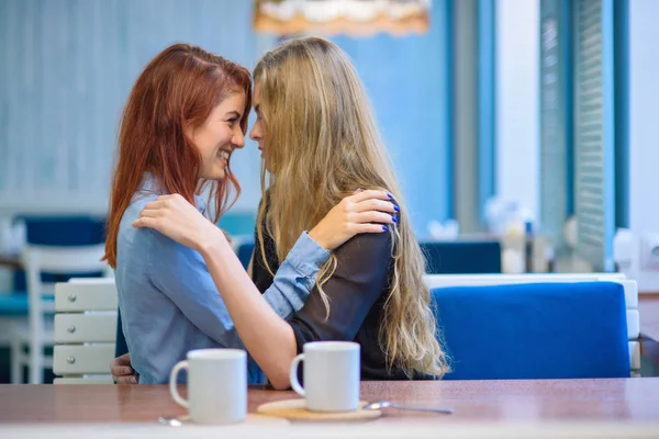 Relaties met hetzelfde geslacht. Gelukkig lesbisch paar zitten in een café. Meisjes houden zachtjes handen vast en drinken koffie. Omhelzing van liefdevolle vrouwen. Lgbt. Twee beste vrienden in café. — Stockfoto