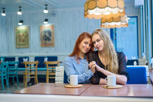 Одностатеві стосунки. Щаслива лесбійська пара сидить у кафе. Дівчата обережно тримають руки і п'ють каву. Обійми люблячих жінок. ЛГБТ. Дві найкращі друзі в кафе . — стокове фото