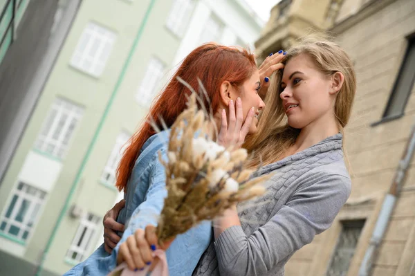 Relaties met hetzelfde geslacht. Gelukkig lesbisch paar met gedroogde bloemen. Twee mooie vrouwen knuffelen elkaar op een date. Boeket op de voorgrond. Close-up tot koppel handen. Lgbt. — Stockfoto