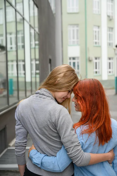 Gleichgeschlechtliche Beziehungen. Ein glückliches lesbisches Paar ging die Straße entlang und umarmte sich sanft um die Taille. den Rücken zweier schöner Frauen bei einem Date mit einem Strauß getrockneter Blumen. lgbt. — Stockfoto