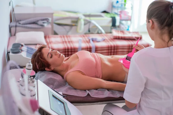 Läkaren applicerar gelen på patienternas mage före kavitation. Anticellulitprocedur. Icke-kirurgisk sifferkorrigering. Skönhetssalong. — Stockfoto