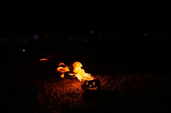 Lenguas de llama en una calabaza. Jack-o-linterna en llamas sobre un fondo negro. Símbolo de Halloween en el suelo. Truco o trato. De cerca. . — Foto de Stock