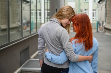 Eşcinsel ilişkiler. Mutlu bir lezbiyen çift cadde boyunca yürüdü ve yavaşça bel etrafında birbirlerine sarılmak. Kurutulmuş çiçek bir buket ile bir tarihte iki güzel kadının sırtı. Lgbt.