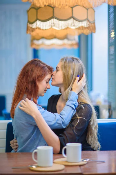 Relaciones del mismo sexo. Feliz pareja lesbiana sentada en un café. Las niñas suavemente tomados de la mano y beber café. Abrazo de amar a las mujeres. LGBT. Dos mejores amigos en la cafetería . — Foto de Stock