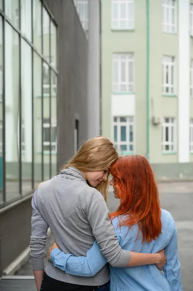 Gleichgeschlechtliche Beziehungen. Ein glückliches lesbisches Paar ging die Straße entlang und umarmte sich sanft um die Taille. den Rücken zweier schöner Frauen bei einem Date mit einem Strauß getrockneter Blumen. lgbt. — Stockfoto