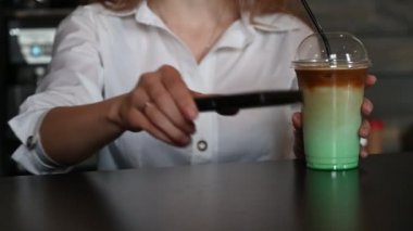 Bir müşteri cep telefonuyla kahve alır. Bir bayan müşteri siparişi bir kafede cep telefonuyla öder..