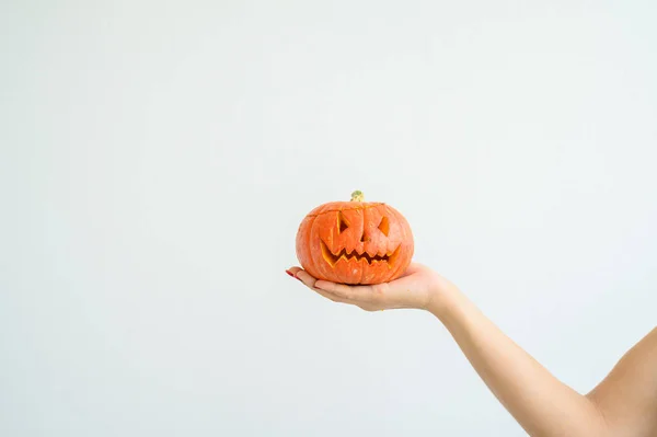 Weibliche Hand, die einen Kürbis zu Halloween hält. Nahaufnahme Jack-o-Laterne Cover auf weißem Hintergrund am Vorabend aller Heiligen. Frontansicht. Hand für den Urlaub gemacht. Trick oder Treatment. — Stockfoto