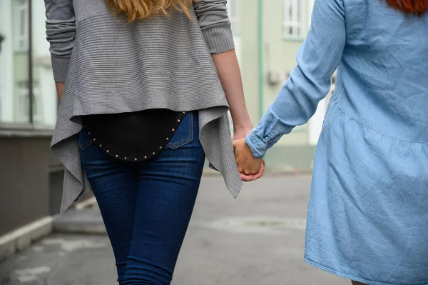 同性関係。幸せなレズビアンのカップルの手を握って通りを歩く。ドライフラワーの花束を持つ日付に2人の美しい女性の背中。Lgbt. — ストック写真