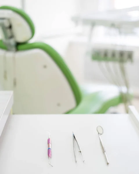 Sterilní nástroje leží na stole v ordinaci zubaře. Zrcadlo, pinzeta a sonda jsou na stole doktora. Ústní hygiena, prevence, vyšetření. — Stock fotografie