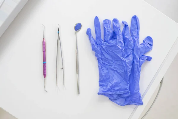 Tabela de dentistas com ferramentas estéreis em uma vista superior de fundo branco. Um espelho, pinças, uma sonda e luvas estão na mesa do médico. Higiene oral, prevenção da cárie, exame . — Fotografia de Stock