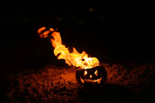 Tungor av flamma i en pumpa. Jack-o-Lantern i brand på en svart bakgrund. Halloween symbol på marken. Bus eller godis. Närbild. — Stockfoto