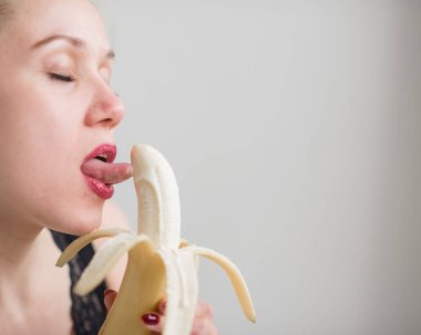 Yüzün, dudakların, genç, Avrupalı bir kızın dilinin yakın çekim ilerki, büyük sarı, tatlı bir muz yalama.