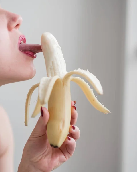 Primer plano de la cara, labios, lengua de una joven europea lamiendo un gran plátano amarillo y dulce . —  Fotos de Stock