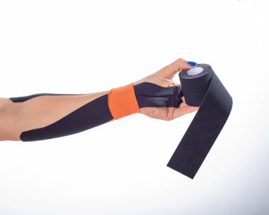 Hastalıklı bir bilek için fizyoterapi. Alternatif tıp. Yaralanmaları olan sporcular için yapışkan bant. Yaralı bir kol için destek. Beyaz bir arka plan üzerinde Kadın el kinesiotape bir rulo tutar.